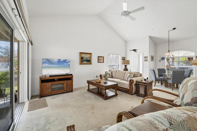 carpeted living room featuring ceiling fan with notable chandelier and high vaulted ceiling