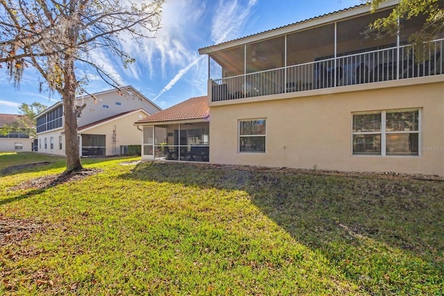 back of property with a sunroom and a yard