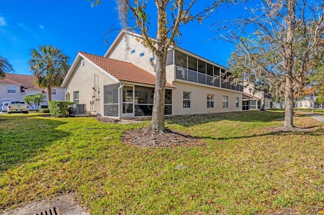 rear view of property featuring central AC unit, a yard, and a sunroom