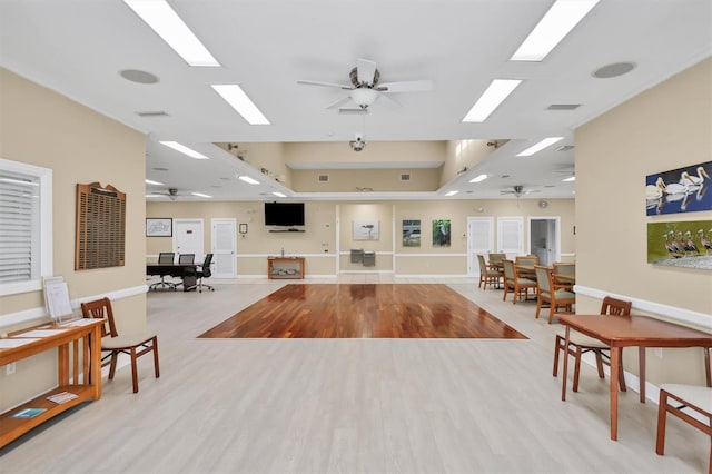 interior space with ceiling fan, light wood-type flooring, and a skylight