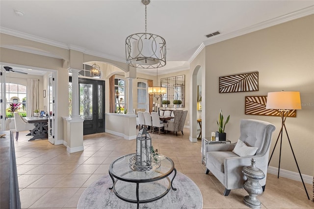 tiled entrance foyer with ornate columns, crown molding, and an inviting chandelier