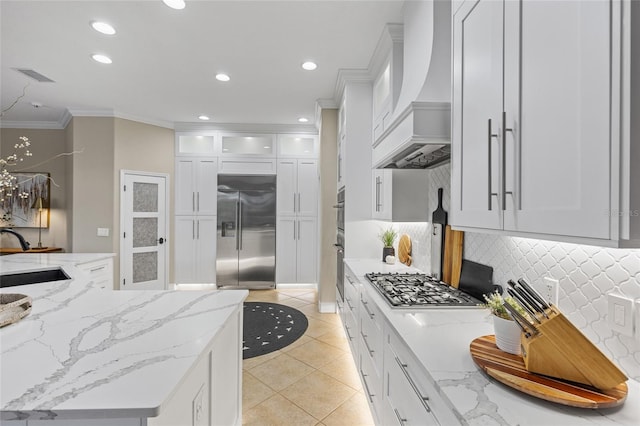 kitchen with sink, custom exhaust hood, stainless steel appliances, and white cabinets