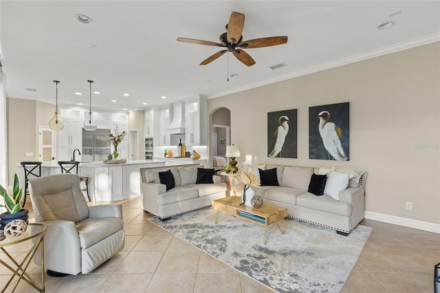 living room featuring light tile patterned floors, crown molding, sink, and ceiling fan