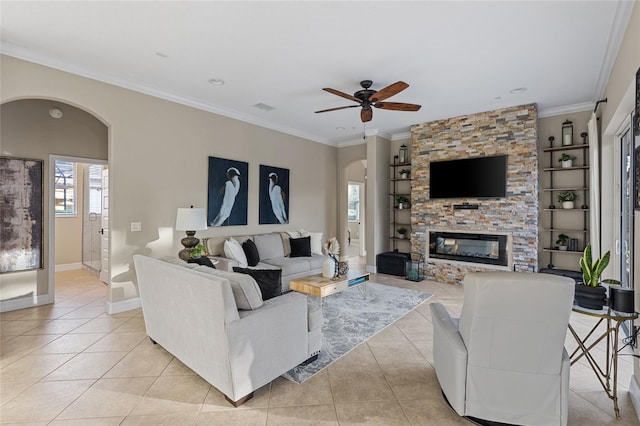 living room featuring ceiling fan, ornamental molding, a fireplace, and light tile patterned floors