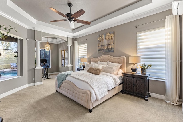 carpeted bedroom featuring crown molding, ceiling fan, a tray ceiling, and ornate columns