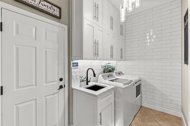 laundry room with sink, tile walls, washing machine and dryer, cabinets, and light tile patterned flooring