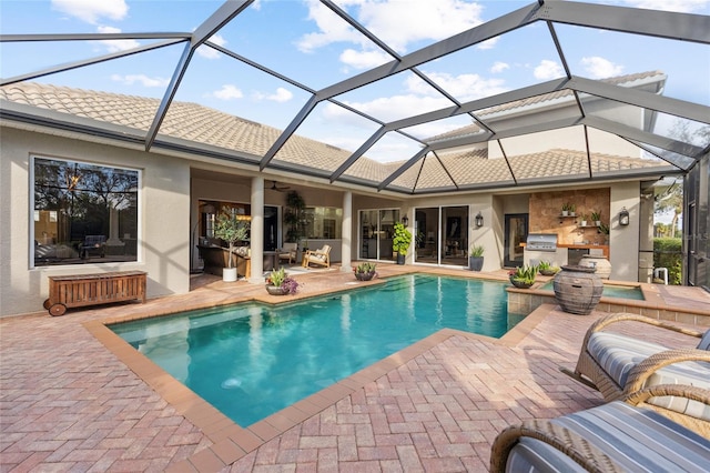 view of swimming pool with a patio area, glass enclosure, and an outdoor kitchen