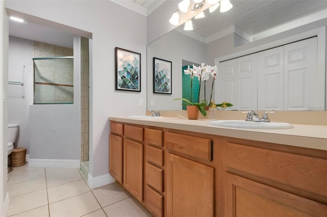 bathroom with tile patterned flooring, tiled shower, vanity, ornamental molding, and toilet