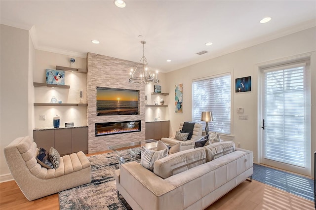 living room with a stone fireplace, crown molding, a chandelier, light wood-type flooring, and built in features