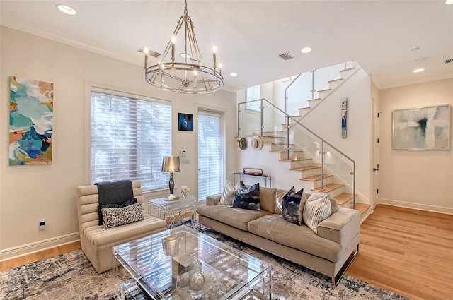 living room with ornamental molding, a notable chandelier, and light wood-type flooring