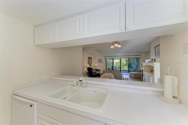 kitchen with white dishwasher, sink, and white cabinets