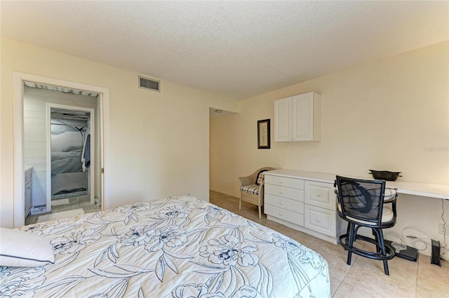 tiled bedroom featuring built in desk and a textured ceiling