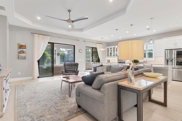 tiled living room featuring ceiling fan and a raised ceiling