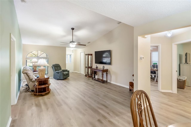 living room featuring ceiling fan, lofted ceiling, a textured ceiling, and light hardwood / wood-style floors