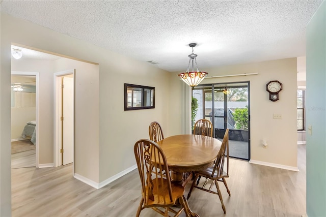 dining room with a textured ceiling and light wood-type flooring