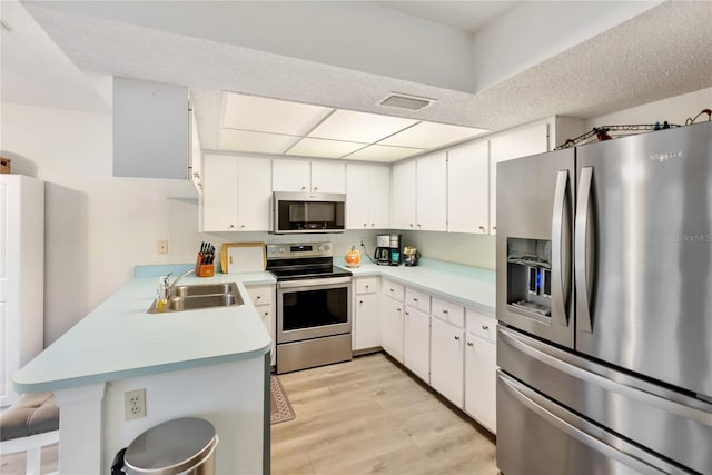 kitchen featuring sink, white cabinets, kitchen peninsula, stainless steel appliances, and light wood-type flooring