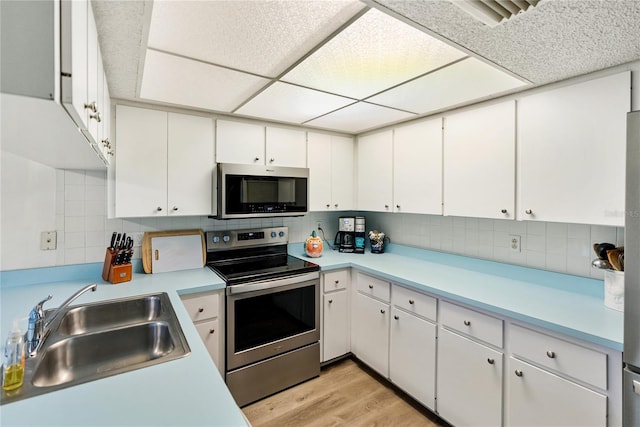 kitchen with appliances with stainless steel finishes, sink, decorative backsplash, and white cabinets