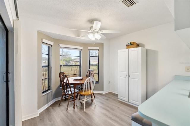 dining room with ceiling fan, light hardwood / wood-style floors, and a textured ceiling