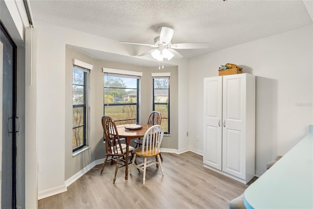 dining space with ceiling fan, light hardwood / wood-style floors, and a textured ceiling