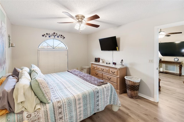 bedroom featuring ceiling fan, light hardwood / wood-style flooring, and a textured ceiling