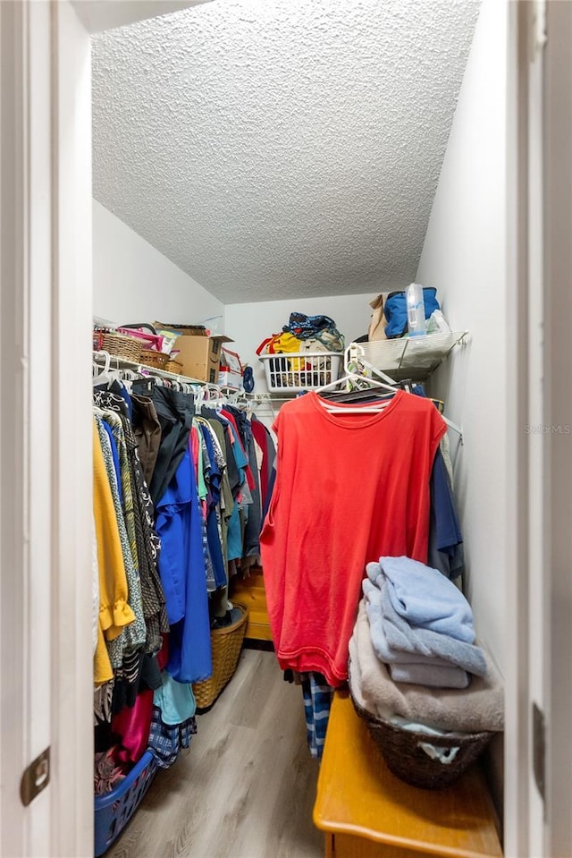 walk in closet featuring hardwood / wood-style flooring and vaulted ceiling