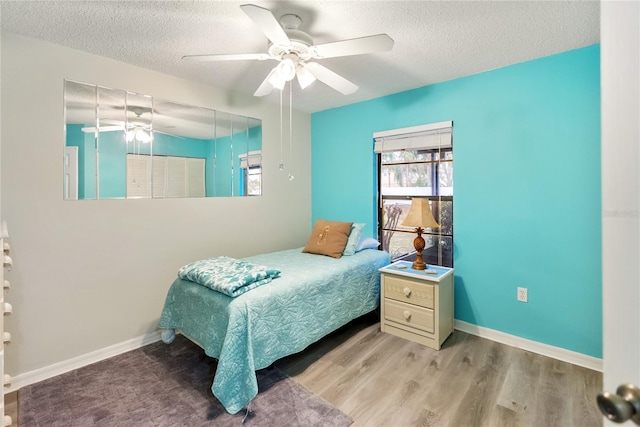 bedroom featuring ceiling fan, a textured ceiling, and light wood-type flooring