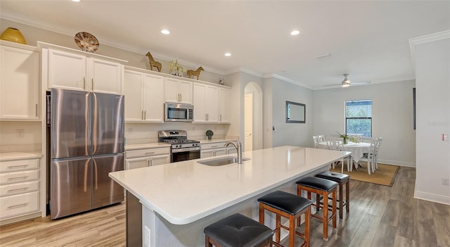 kitchen featuring sink, a breakfast bar area, appliances with stainless steel finishes, white cabinetry, and a center island with sink