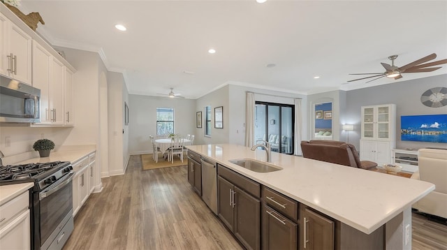 kitchen featuring sink, dark brown cabinets, stainless steel appliances, white cabinets, and a center island with sink