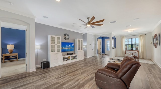 living room with wood-type flooring, ornamental molding, and ceiling fan