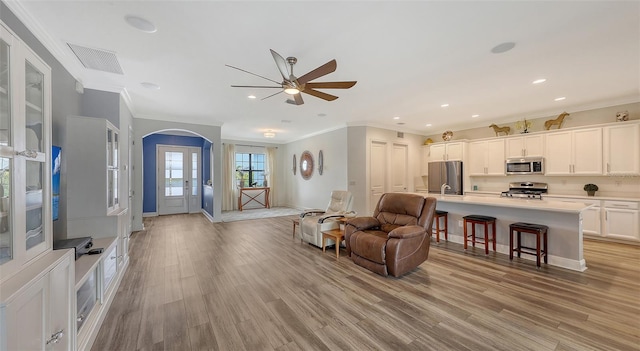 living room with crown molding, sink, and light hardwood / wood-style flooring