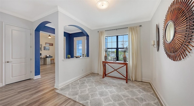 entryway with ornamental molding and light hardwood / wood-style floors