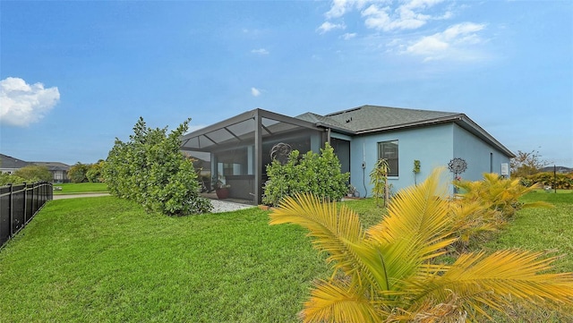 rear view of property with a lanai and a lawn