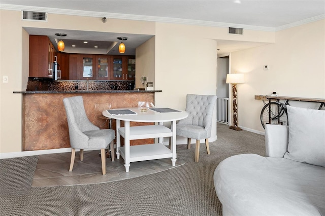 dining room with crown molding, indoor bar, and dark colored carpet