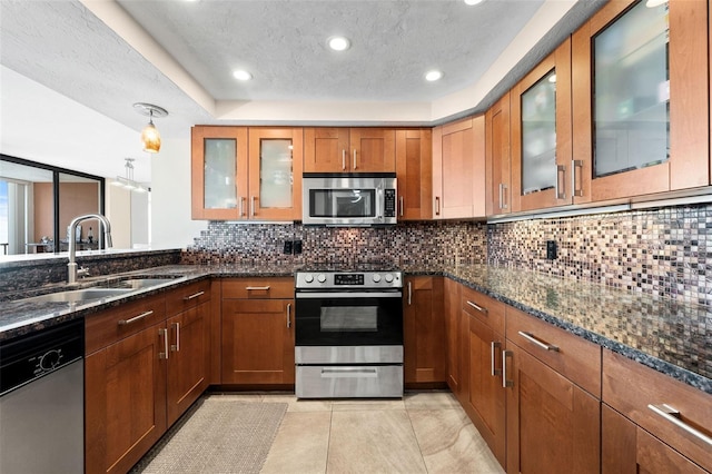 kitchen with sink, dark stone countertops, pendant lighting, stainless steel appliances, and decorative backsplash