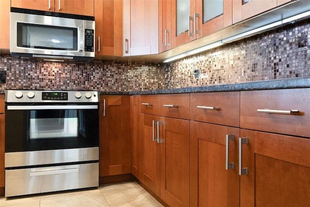 kitchen with tasteful backsplash, appliances with stainless steel finishes, and dark stone counters