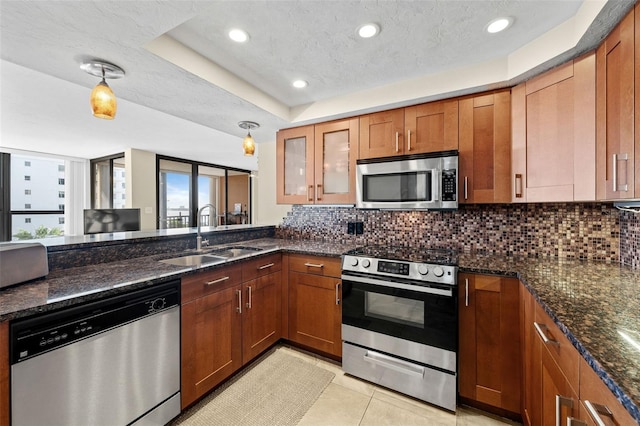 kitchen with sink, light tile patterned floors, appliances with stainless steel finishes, dark stone countertops, and tasteful backsplash