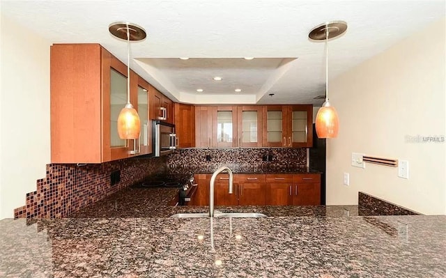 11 Sunset Dr Unit 406, Sarasota, FL 34236 - kitchen with dark stone countertops, backsplash, glass insert cabinets, and a sink