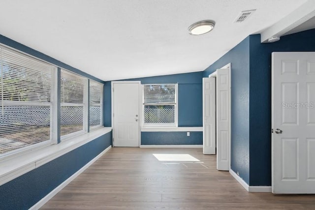 empty room featuring hardwood / wood-style flooring, lofted ceiling, and a textured ceiling