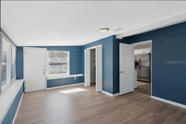 unfurnished bedroom featuring dark wood-type flooring and stainless steel fridge