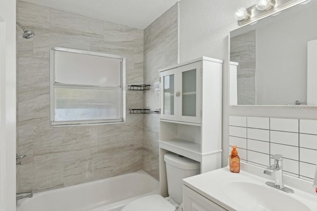 full bathroom featuring tile walls, backsplash, vanity, tiled shower / bath, and toilet