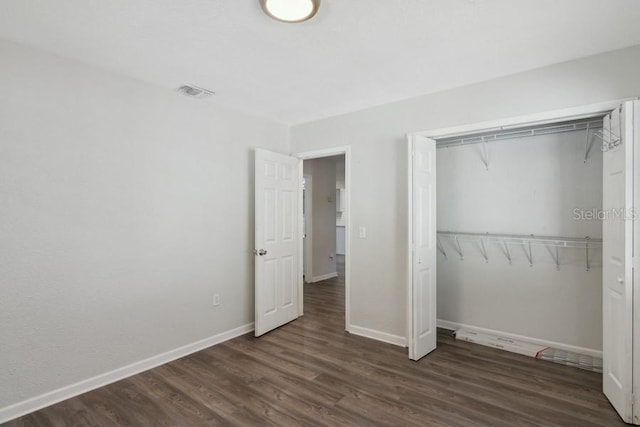 unfurnished bedroom with dark wood-type flooring and a closet