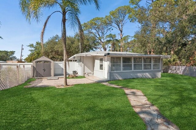 rear view of property featuring a yard and a storage unit