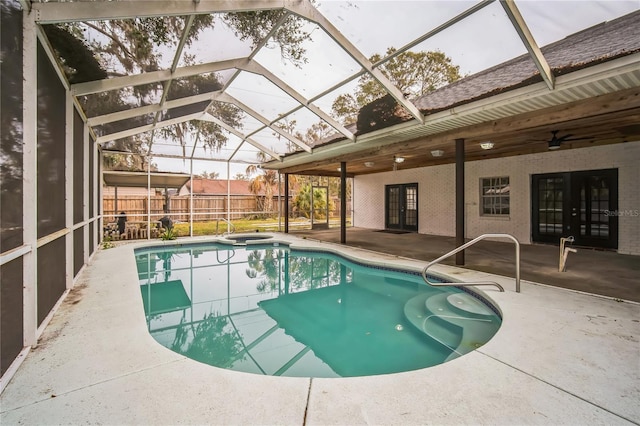 view of swimming pool featuring french doors, ceiling fan, glass enclosure, and a patio area