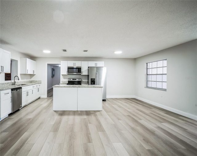 kitchen featuring white cabinetry, sink, a center island, stainless steel appliances, and light wood-type flooring