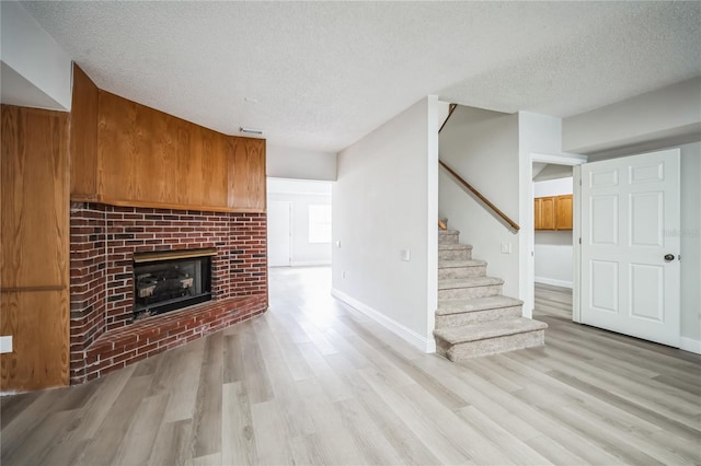 unfurnished living room with light wood-type flooring, a textured ceiling, and a fireplace