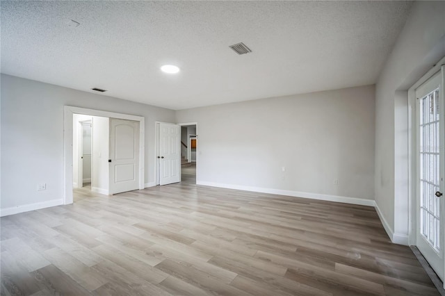 spare room featuring light hardwood / wood-style floors and a textured ceiling