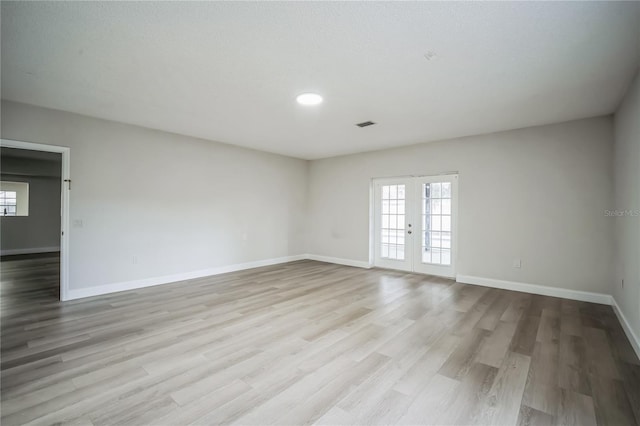 empty room with light hardwood / wood-style floors and french doors