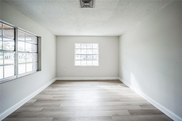 unfurnished room with a textured ceiling and light wood-type flooring