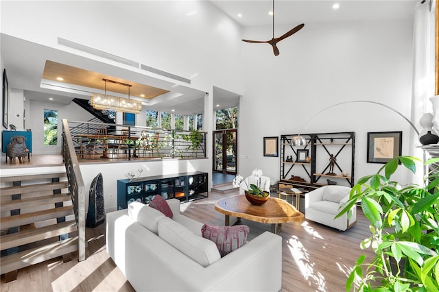 living room with a tray ceiling, light hardwood / wood-style floors, and a notable chandelier