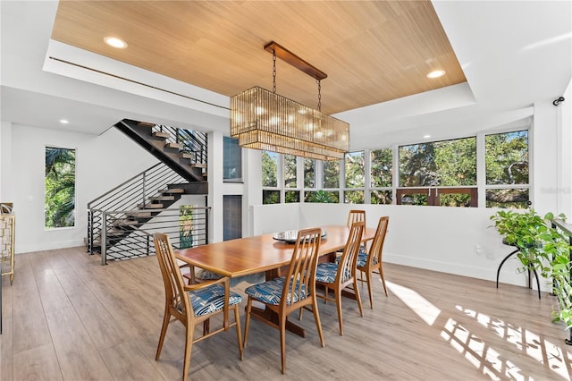 dining room featuring light wood-type flooring, wood ceiling, and a tray ceiling